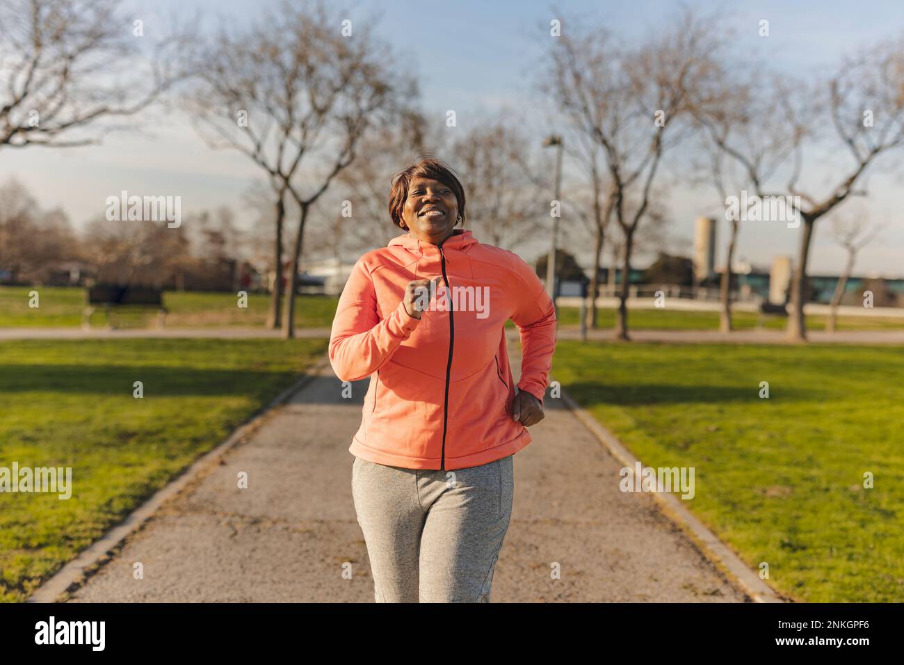 Donna anziana felice che corre al parco Foto Stock