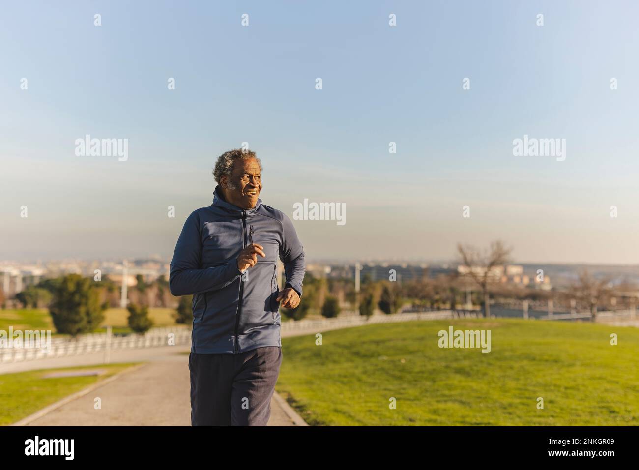 Uomo anziano che corre nel parco nelle giornate di sole Foto Stock