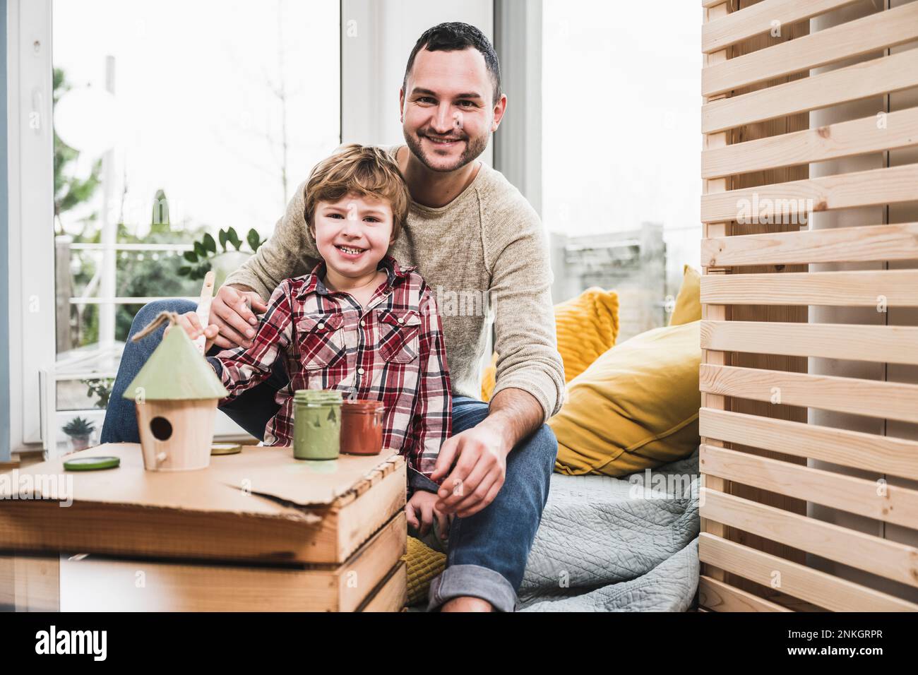 Sorridente padre e figlio con la modella house a casa Foto Stock