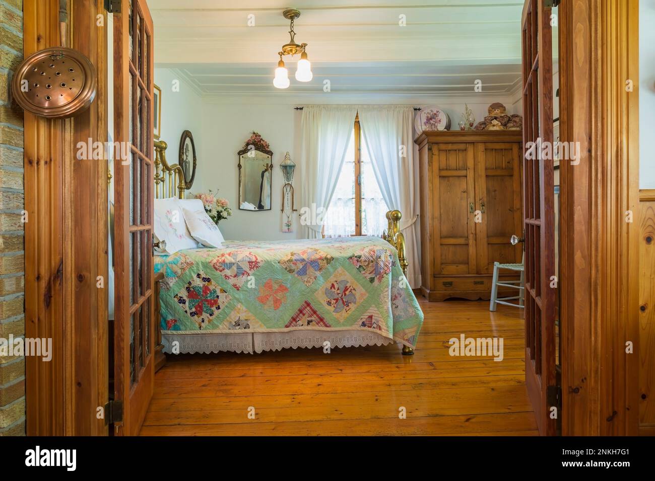 Letto matrimoniale con testata in ottone antico e poggiapiedi, più antico armadio in legno nella camera da letto principale all'interno della vecchia casa del 1840 circa. Foto Stock