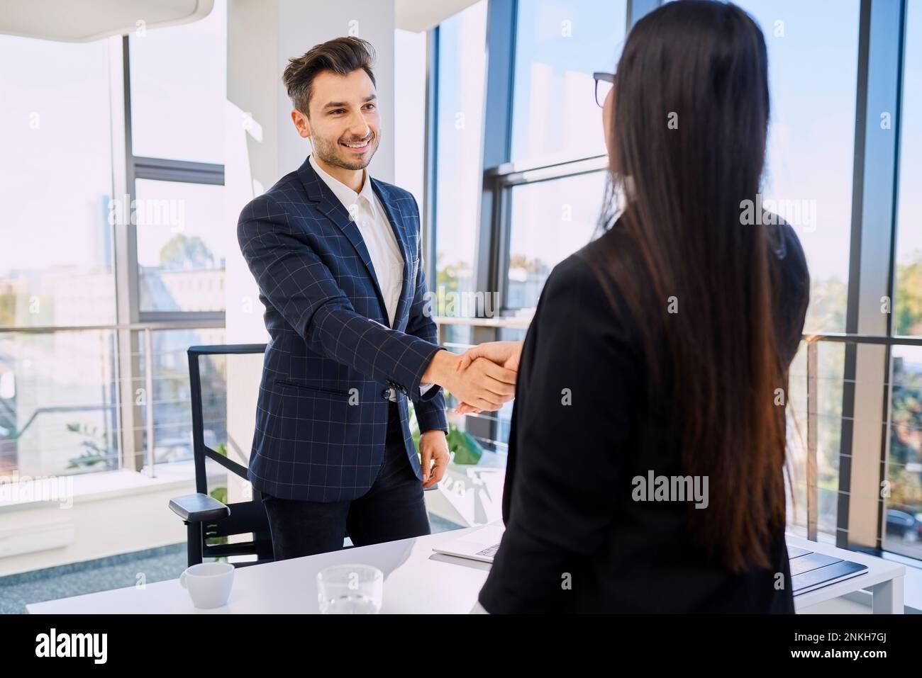 Reclutatore sorridente che fa stretta di mano con il candidato dopo il colloquio in ufficio Foto Stock