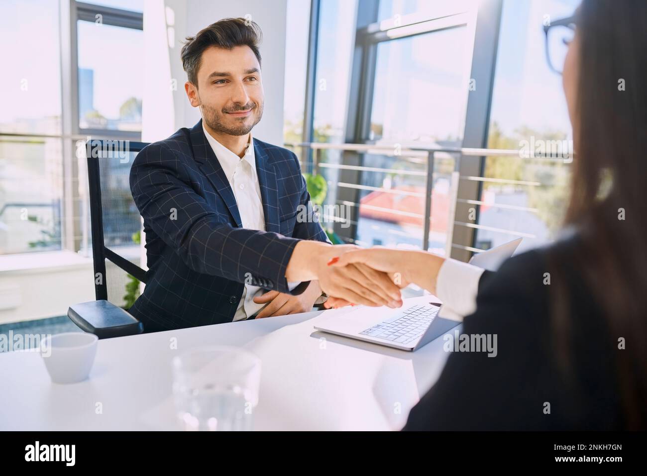 Reclutatore sorridente che fa stretta di mano con il candidato in ufficio Foto Stock