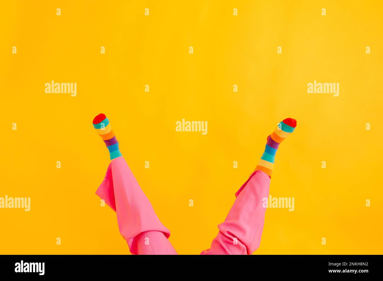 Piedi di donna che indossa calze multicolore su sfondo giallo Foto Stock