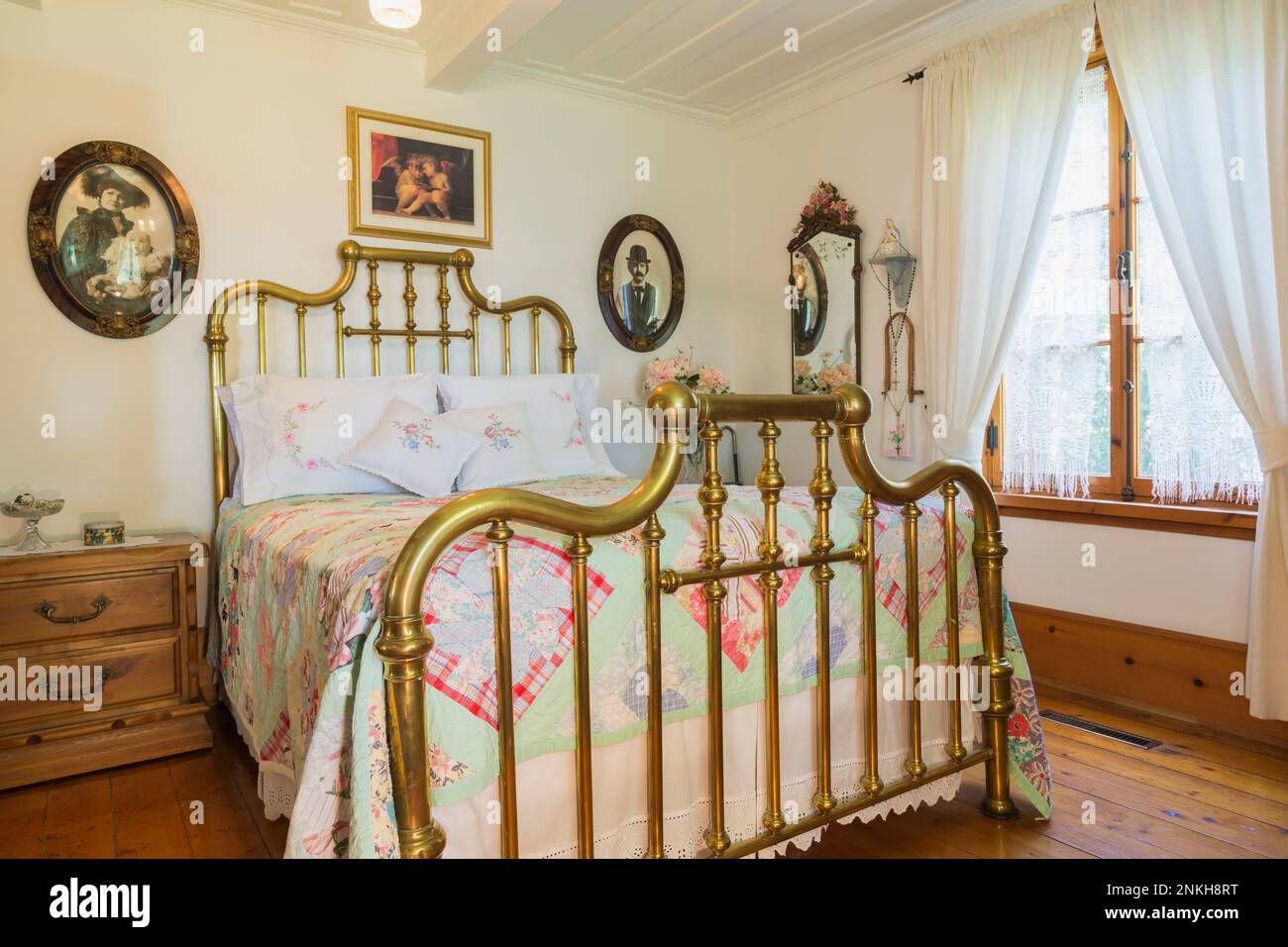 Letto matrimoniale con testiera e poggiapiedi in ottone antico e comodino in legno di pino nella camera da letto principale all'interno della vecchia casa del 1840 circa. Foto Stock