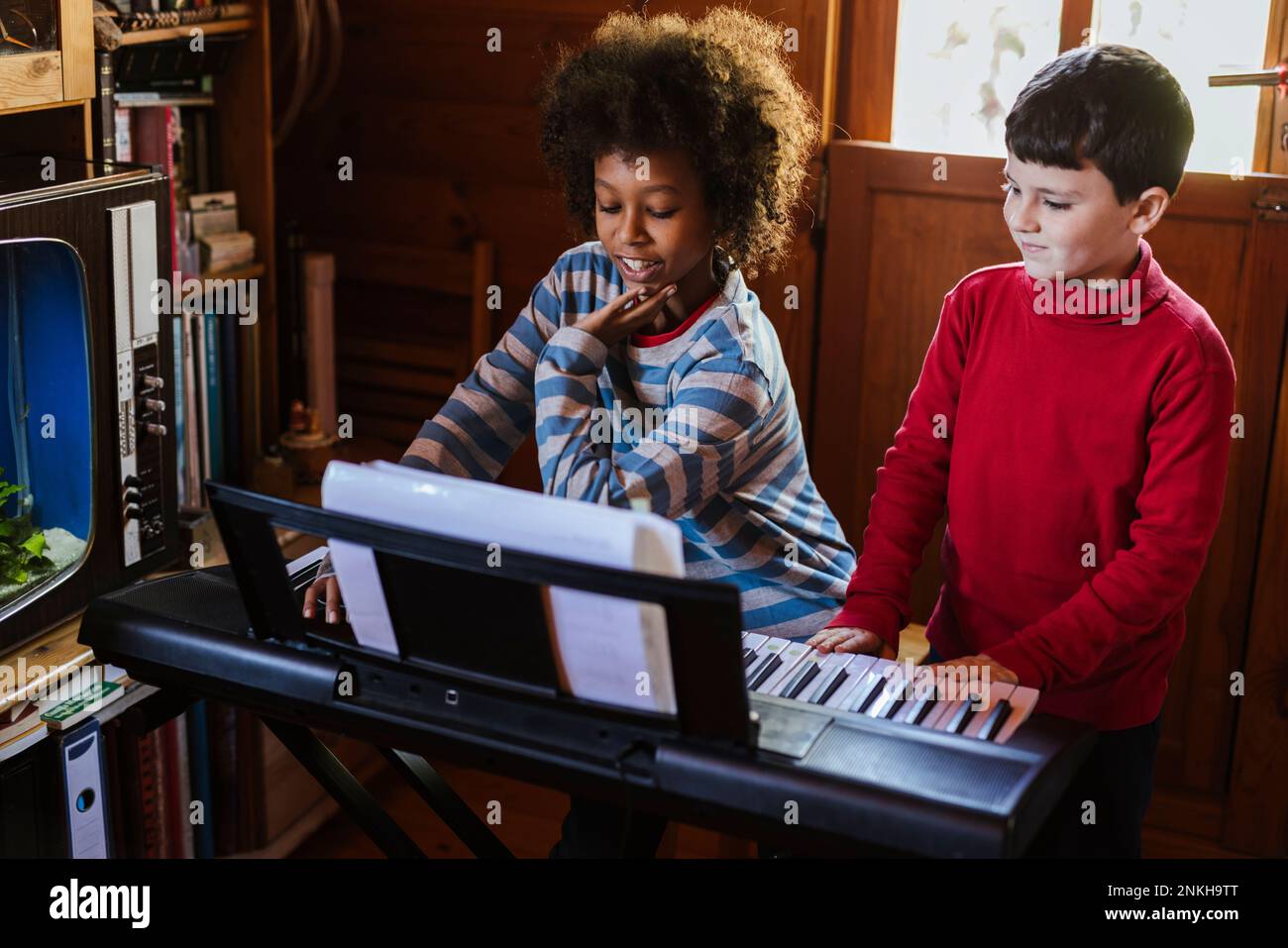 Ragazzo che suona il pianoforte elettrico da un amico a casa Foto Stock