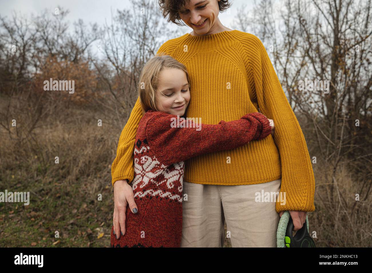 Figlia sorridente abbracciando la madre Foto Stock