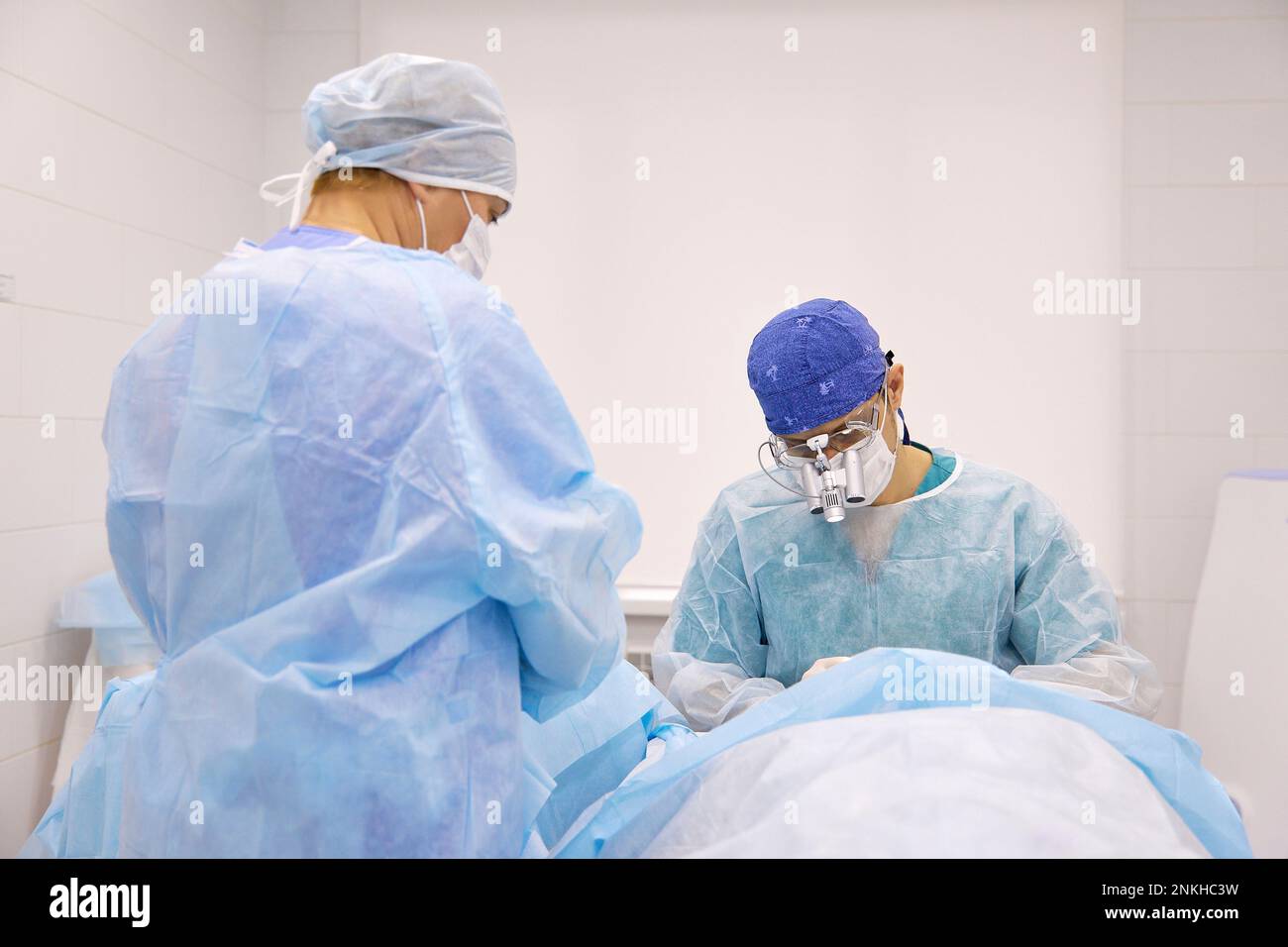Chirurgo con collega che fa chirurgia oculare sul paziente Foto Stock