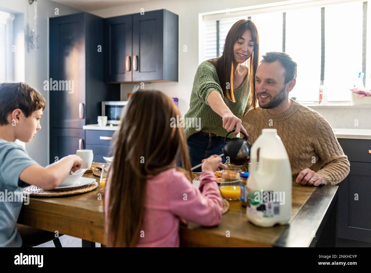 Felice uomo e donna che fa colazione con i bambini a casa Foto Stock