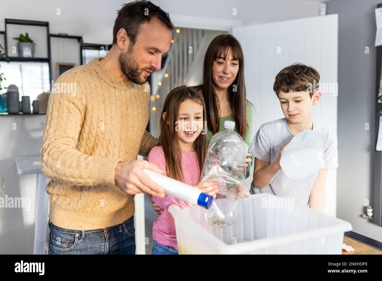 Famiglia felice riciclando la plastica a casa Foto Stock