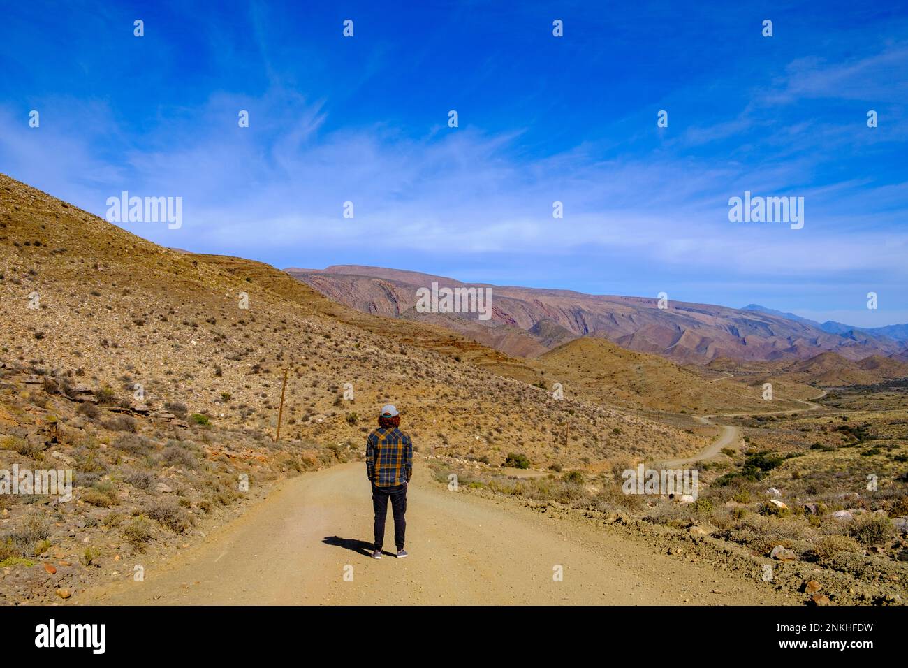 Sud Africa, Provincia del Capo Occidentale, escursionista maschio in piedi nel mezzo di una strada sterrata vuota nel Grande Karoo Foto Stock