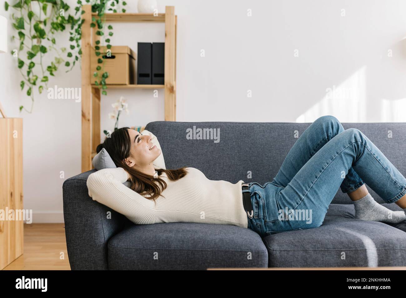 Giovane donna rilassante sul divano di casa Foto Stock