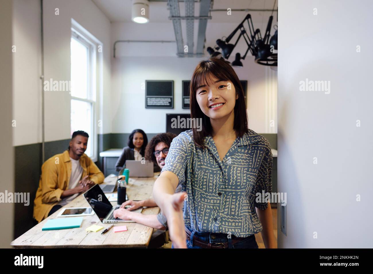 Donna d'affari sorridente che fa la stretta di mano in ufficio Foto Stock