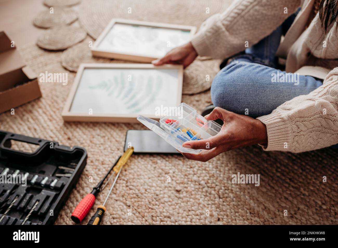 Donna che fa cornici fai da te seduto a casa Foto Stock