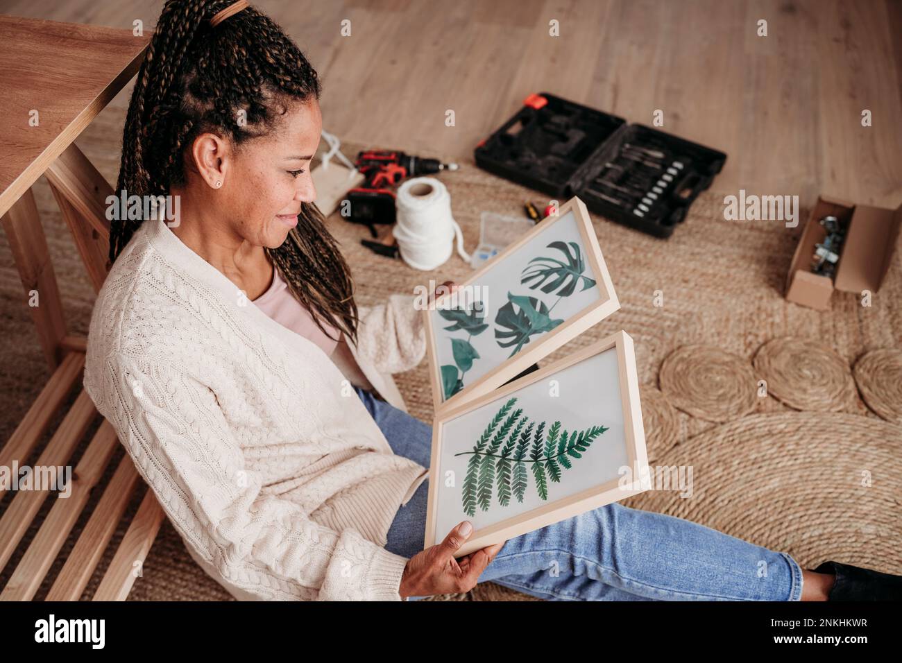 Donna sorridente seduta con cornici a casa Foto Stock