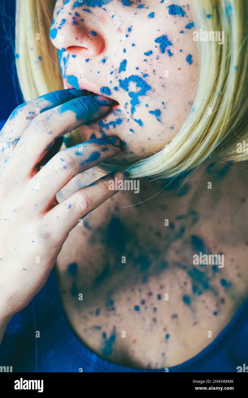 Donna mordente dita ricoperte di vernice blu Foto Stock