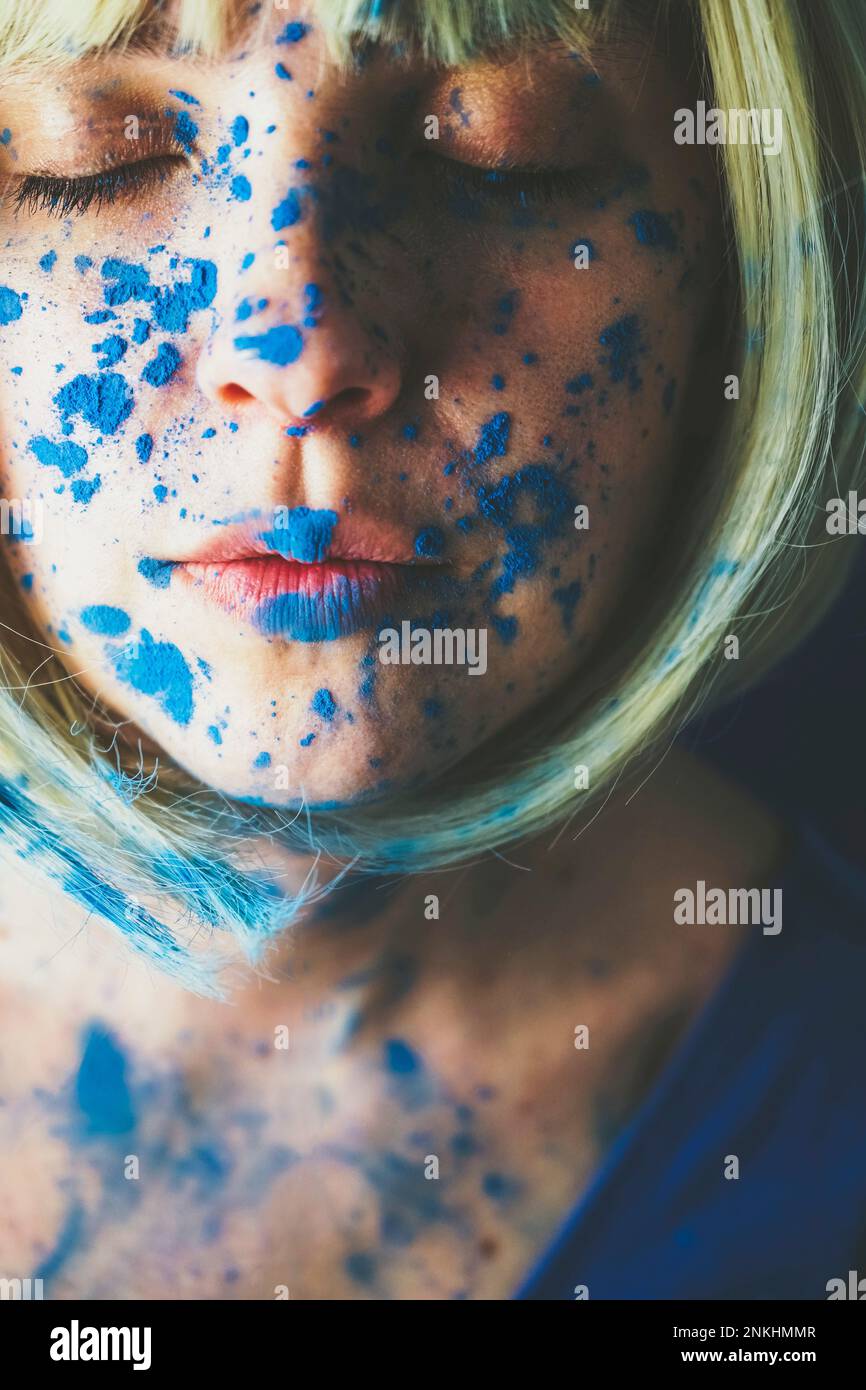Donna con gli occhi chiusi ricoperti di vernice blu Foto Stock