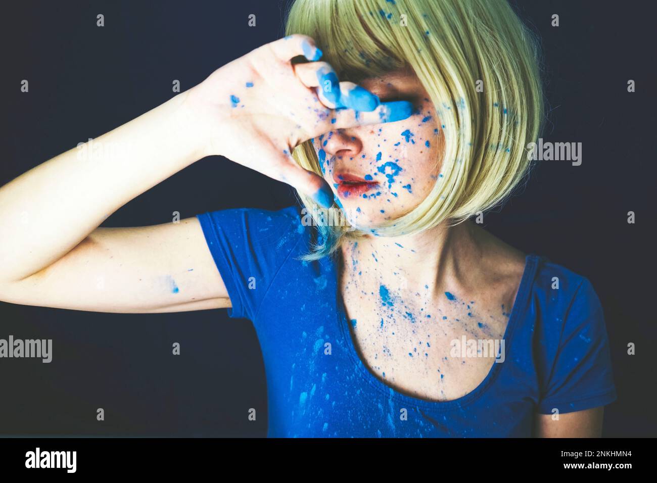 Donna coperta con vernice a polvere blu su sfondo nero Foto Stock