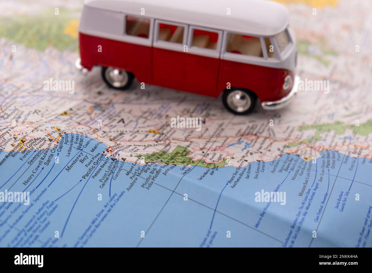 OGDEN, UTAH USA - FEBBRAIO 10 2023 Una VW rossa e bianca in miniatura su una mappa della costa californiana con focalizzazione selettiva sulla baia di Monterey Foto Stock