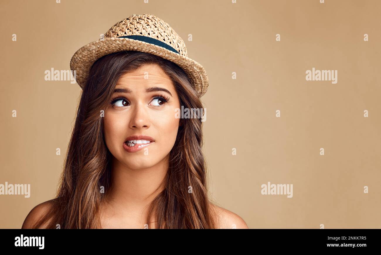 Le sue opzioni abbastanza molto... Studio girato di una bella giovane donna che guarda premurosa su uno sfondo marrone. Foto Stock