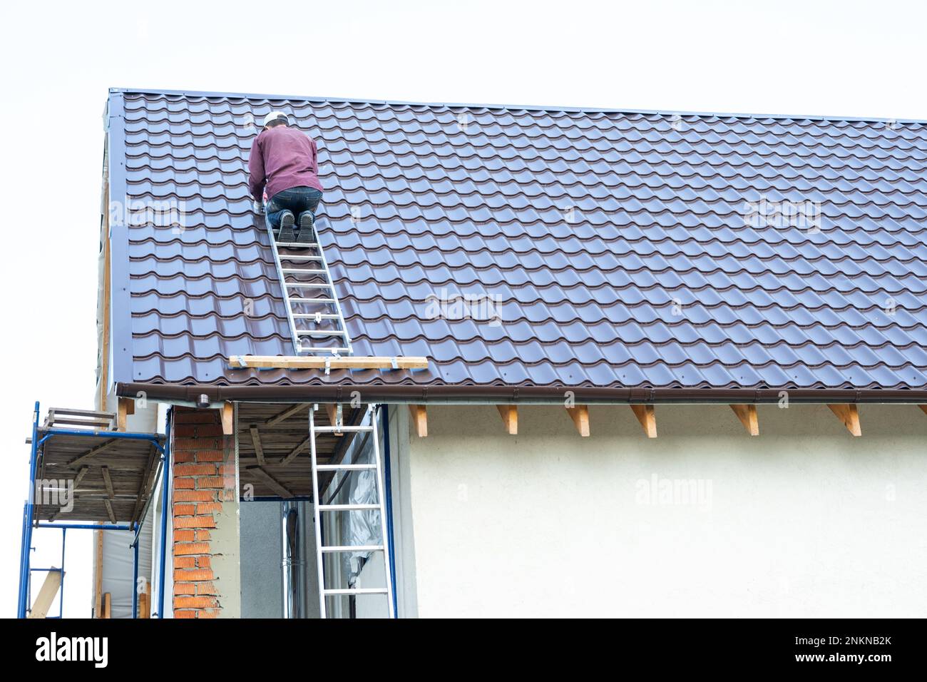 Il maestro per l'installazione di tubi di ventilazione e l'installazione del camino del forno lavora sul tetto della casa Foto Stock