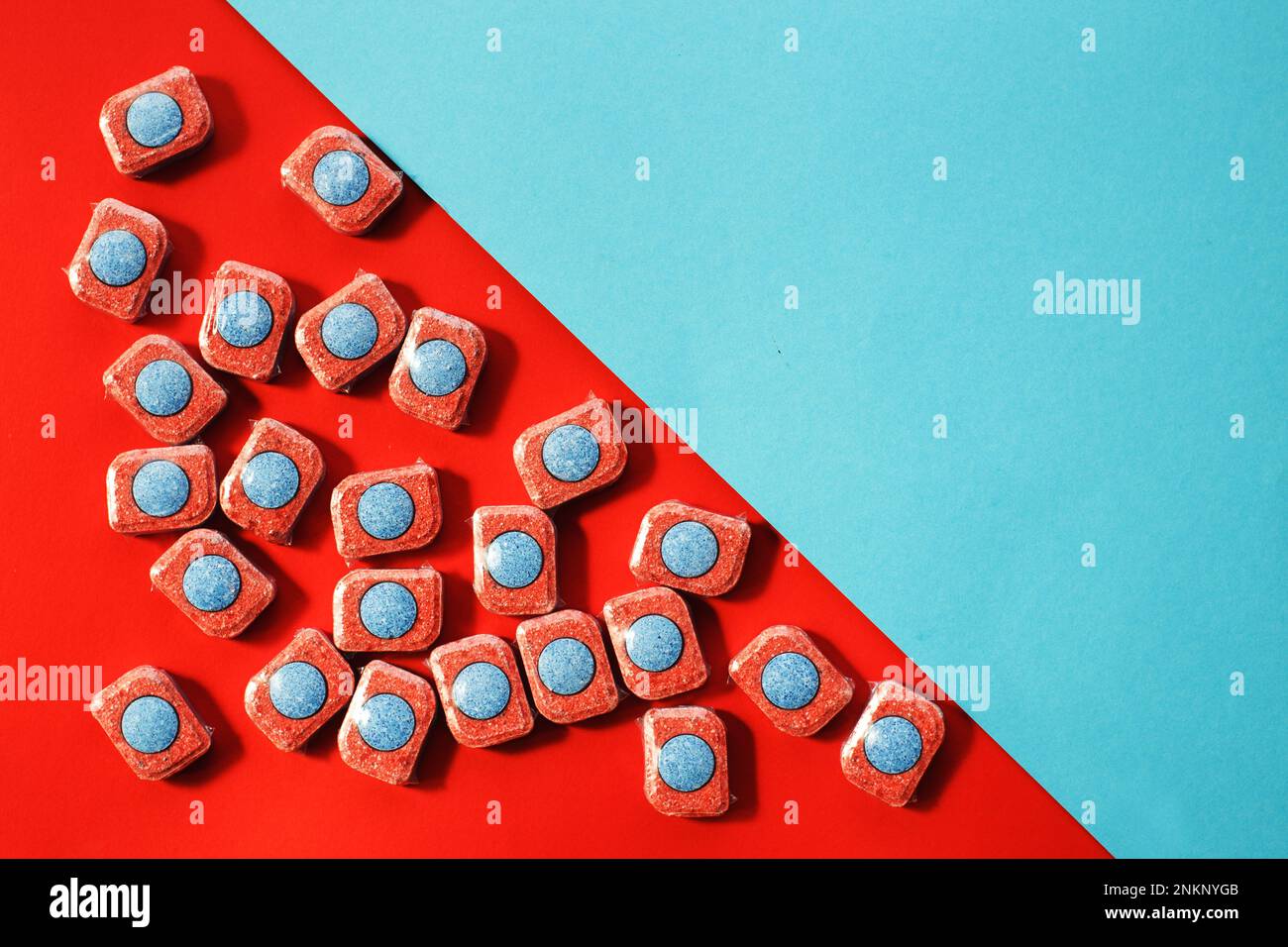 capsule per lavastoviglie da cucina su sfondo blu e rosso. giacitura piatta Foto Stock