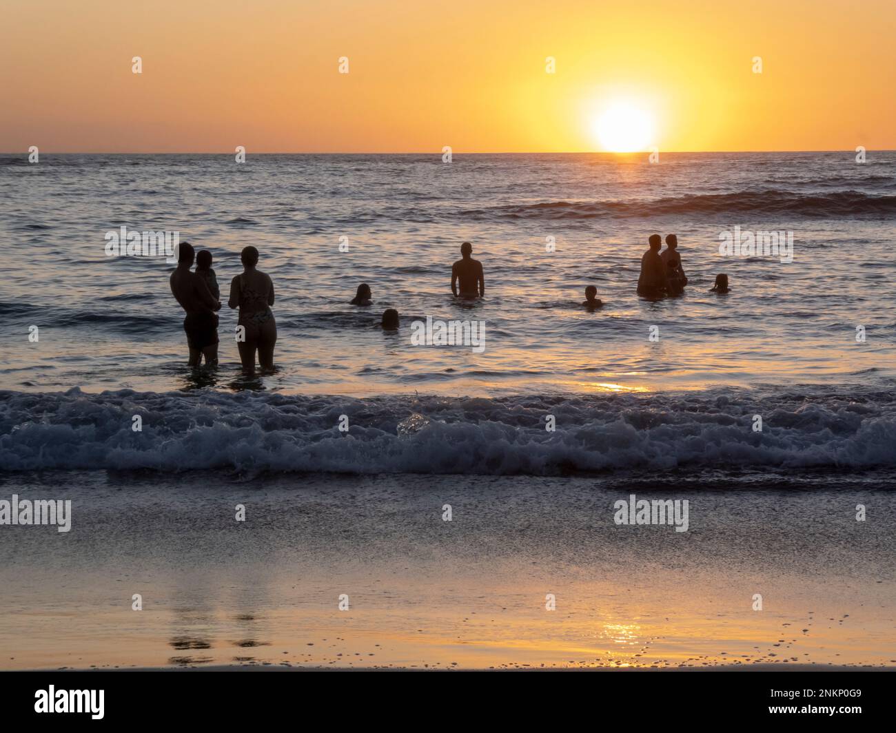 La gente gode gli ultimi raggi del sole di tramonto dal mare in Nosara Costa Rica Foto Stock