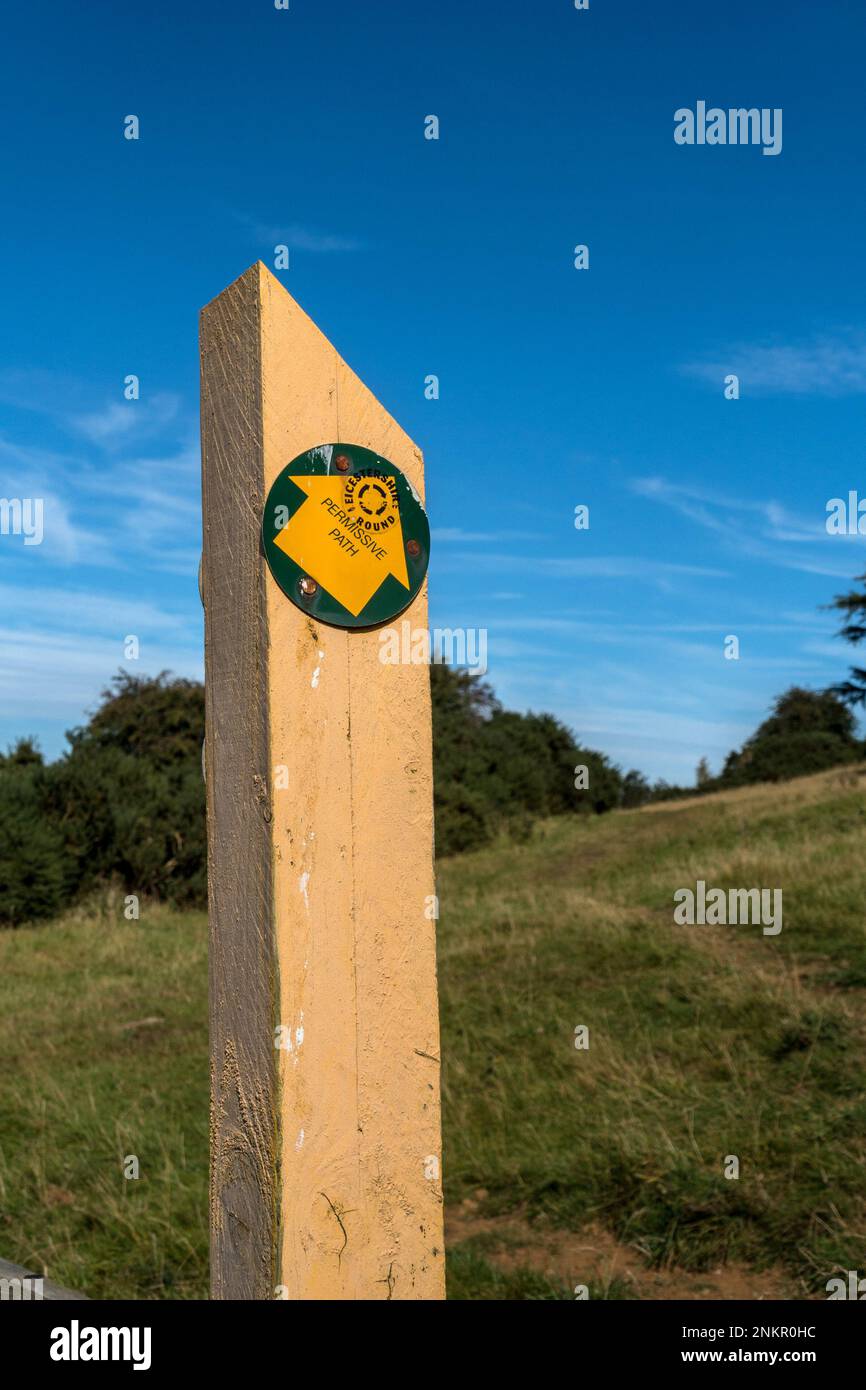 Percorso permissivo in legno dipinto di giallo, Leicestershire percorso rotondo posta marcatore contro il cielo blu con frecce di direzione, Leicestershire, Inghilterra, Regno Unito Foto Stock