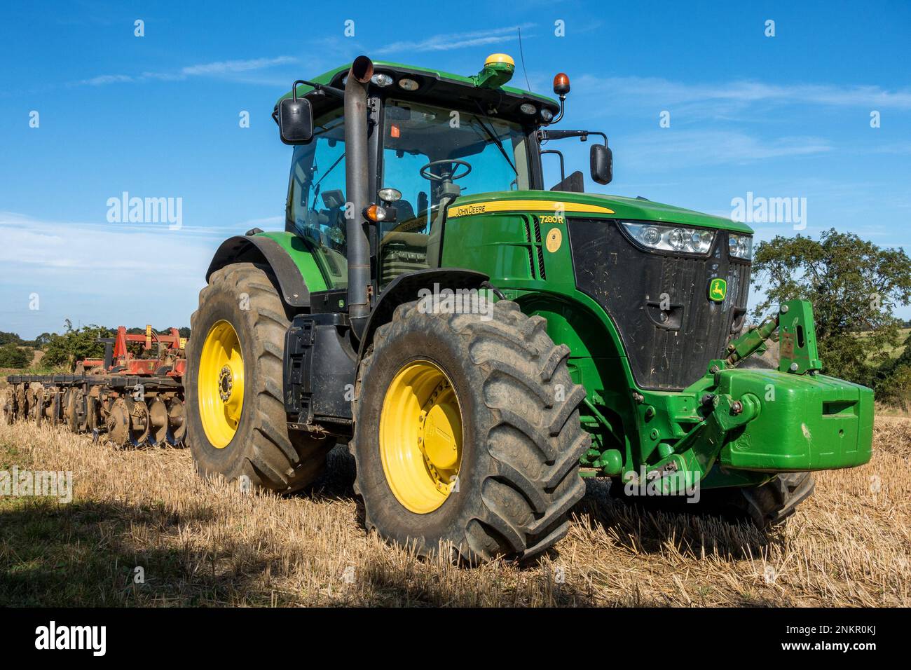 Grande trattore agricolo John Deere a 7280R file, verde brillante, con pneumatici grandi e erpice a dischi parcheggiato a Leicestershire Field, Inghilterra, Regno Unito Foto Stock