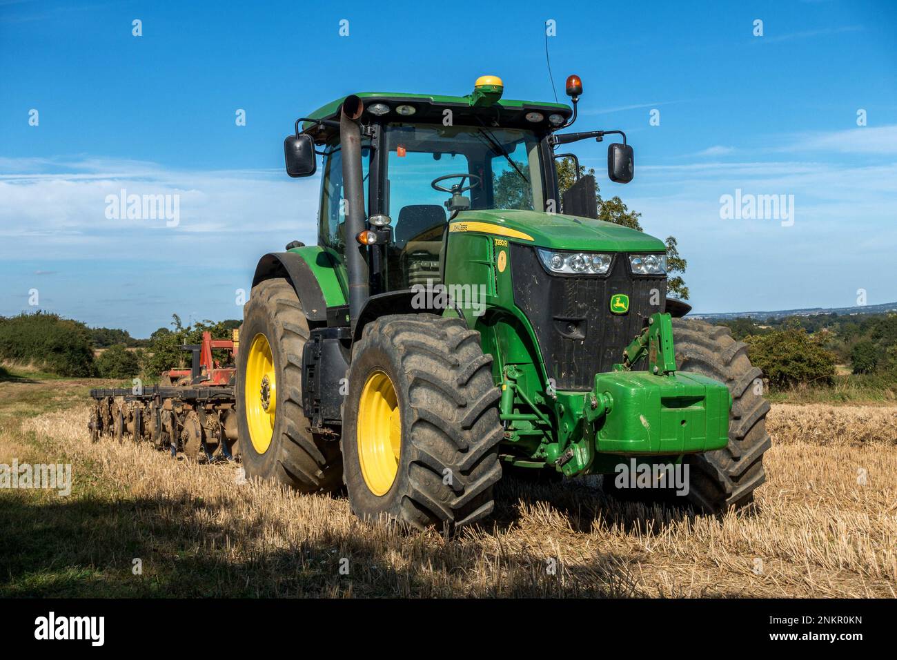 Grande trattore agricolo John Deere a 7280R file, verde brillante, con pneumatici grandi e erpice a dischi parcheggiato a Leicestershire Field, Inghilterra, Regno Unito Foto Stock