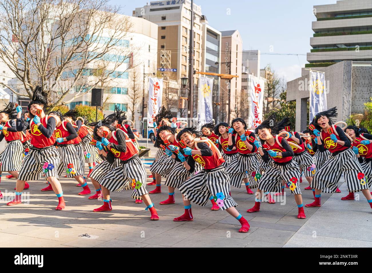 Squadra giapponese di danzatrici Yosakoi bambina che ballano e tengono naruko, clapper, nella piazza della città in occasione dell'annuale festival Kyusyu Gassai a Kumamoto. Foto Stock