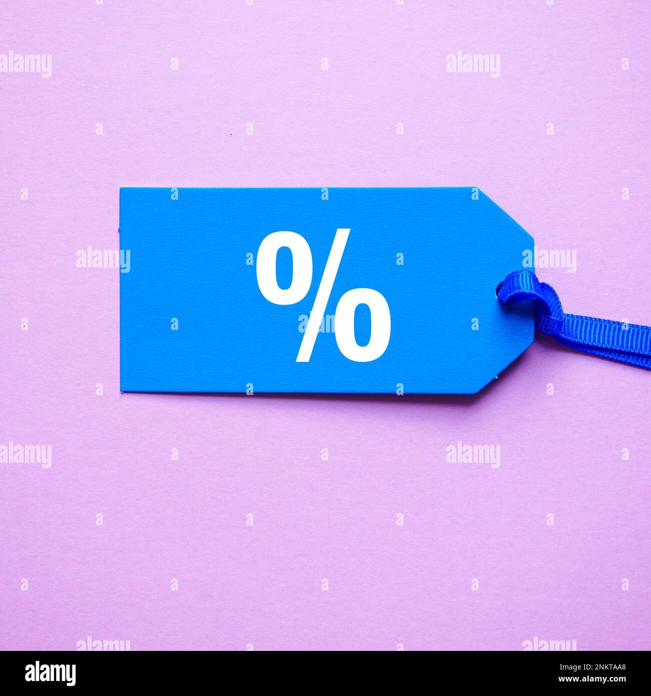simbolo di percentuale sulla fascia di prezzo blu, sfondo rosa Foto Stock