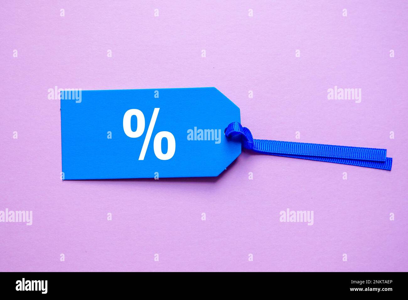 simbolo di percentuale sulla fascia di prezzo blu, sfondo rosa Foto Stock