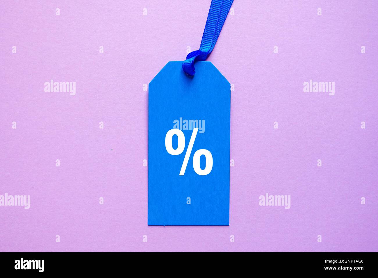 simbolo di percentuale sulla fascia di prezzo blu, sfondo rosa Foto Stock