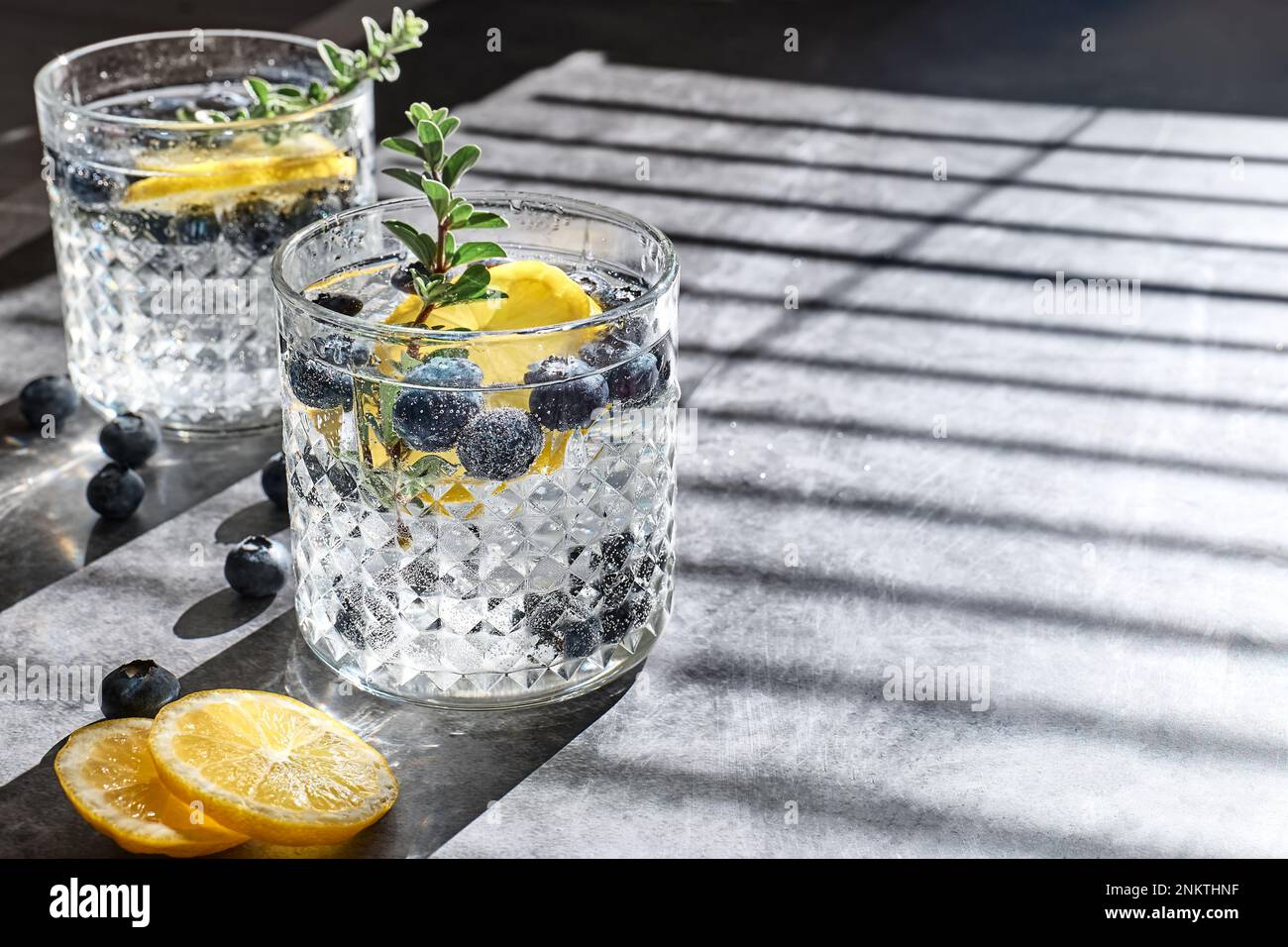 Fresco estate bere mojito mirtillo o mirtillo limonata ghiacciata con fettine di limone, mirtilli, ghiaccio e timo. Foto Stock