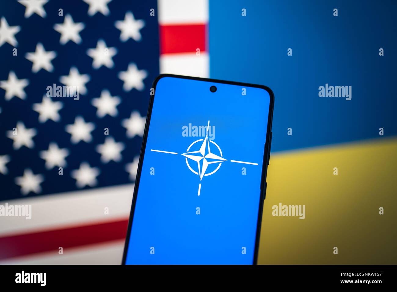 Bandiera della NATO al telefono con bandiera degli Stati Uniti e bandiera dell'Ucraina sullo sfondo. Swansea, Regno Unito - 23 febbraio 2023. Foto Stock