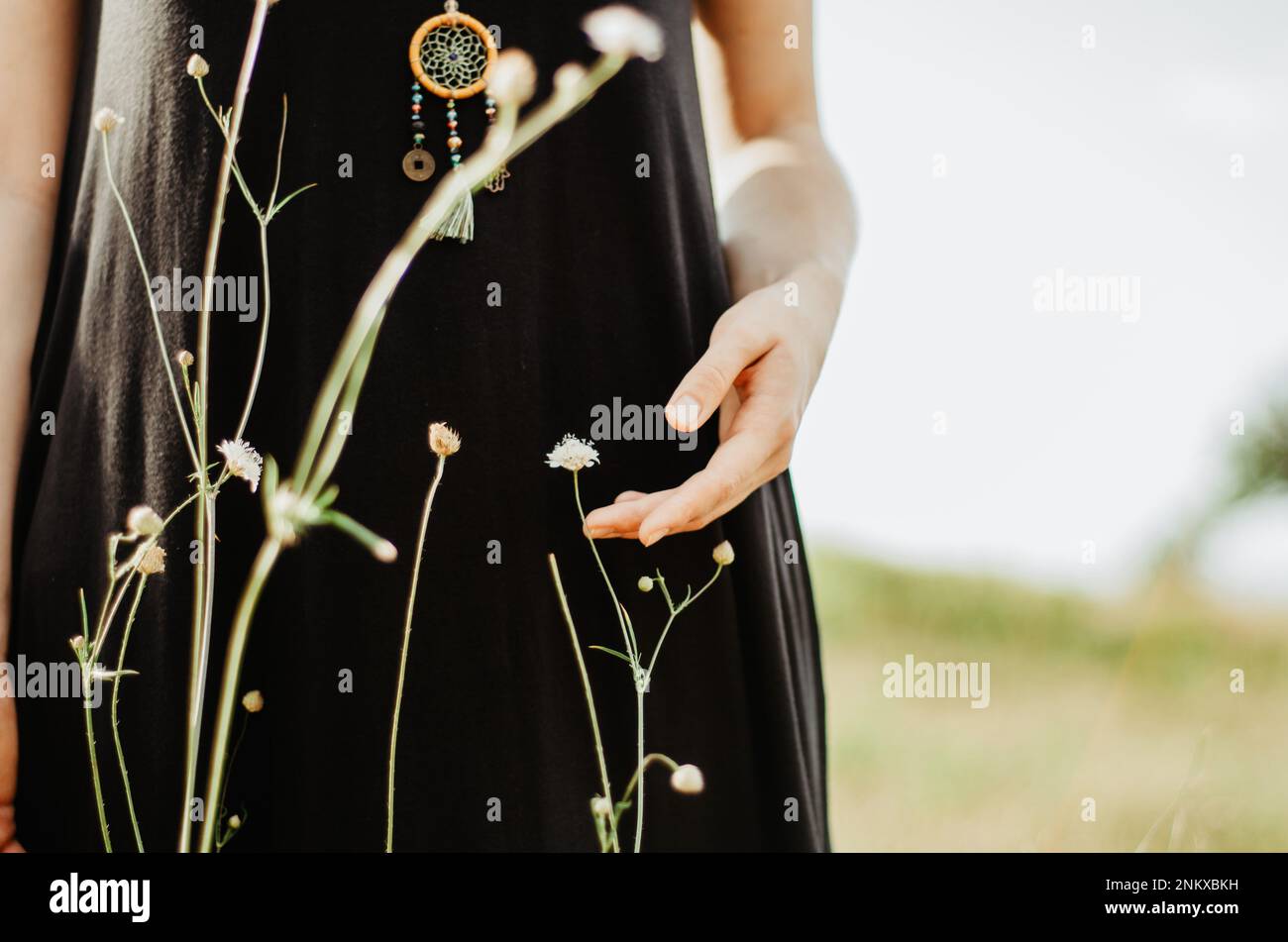 Boho donna con mano toccante fiore selvatico Foto Stock
