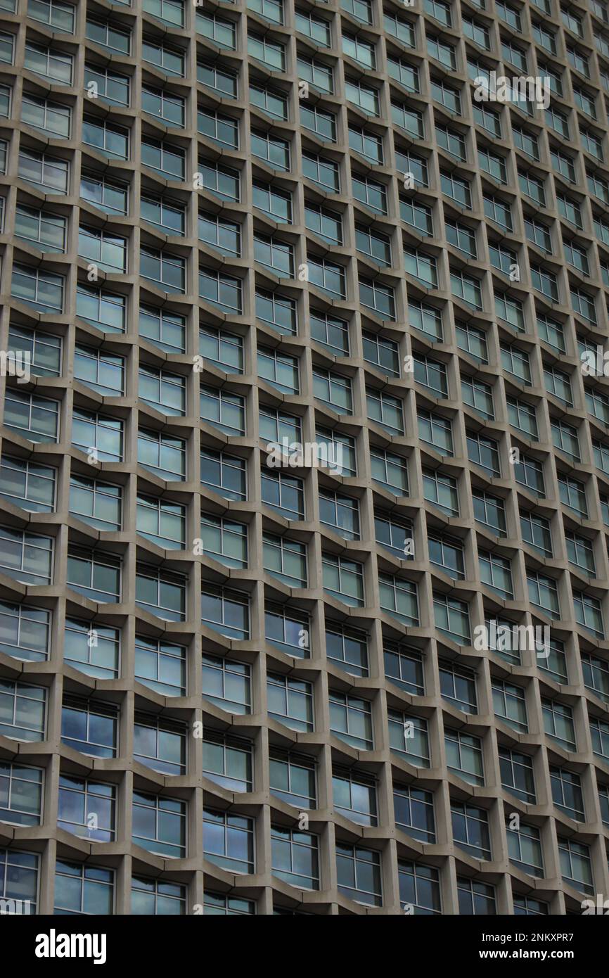 Edificio d'uffici in stile modernista - finestre in vetro a ripetizione di un grattacielo con bordi in cemento. Sfondo grattacielo modernista, texture, carta da parati Foto Stock