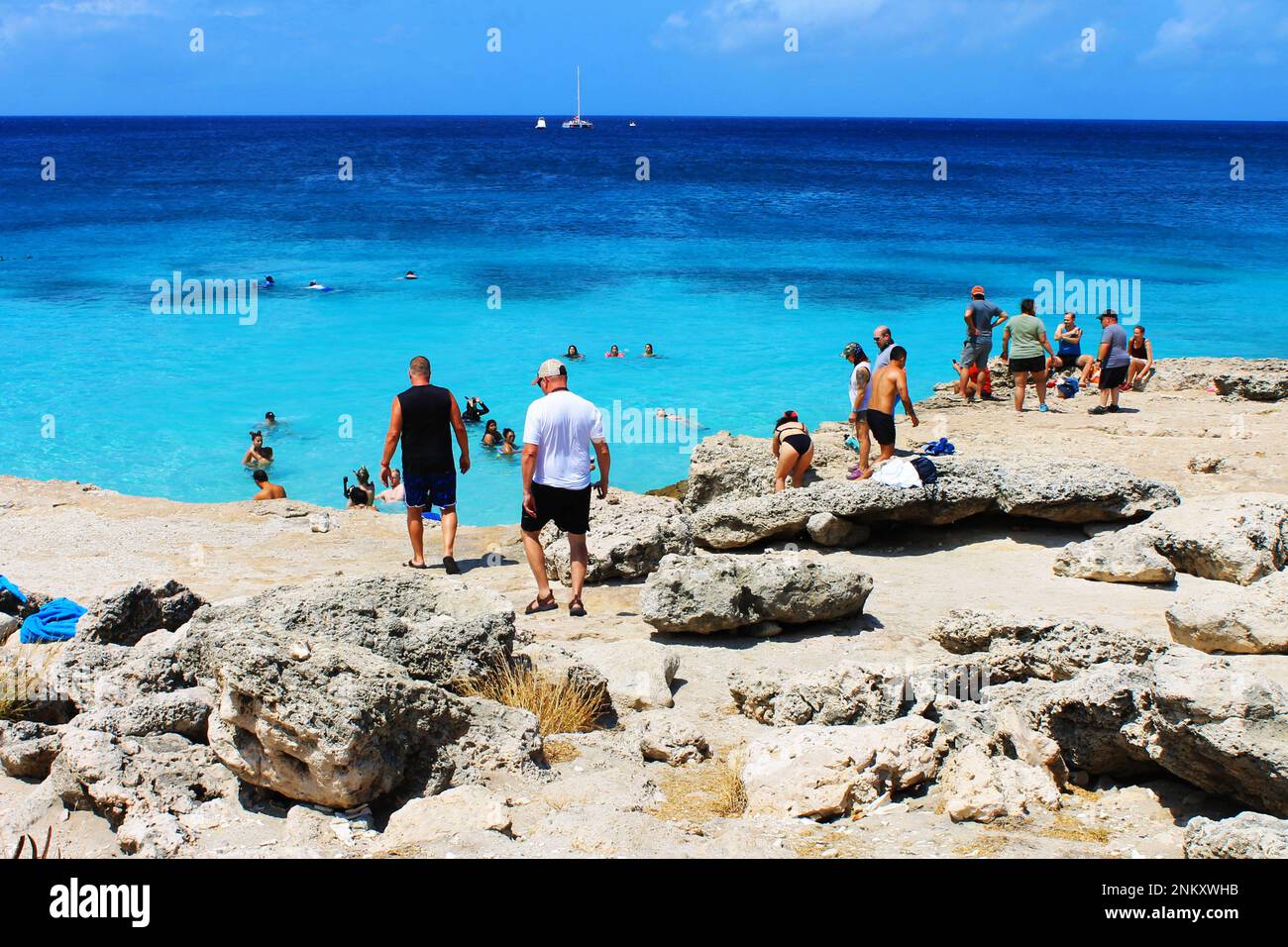 Tres Trappi Beach, Noord, Aruba - 10 marzo 2022. Persone sulla spiaggia e in acqua, la spiaggia è circondata da una formazione di roccia vulcanica. Foto Stock