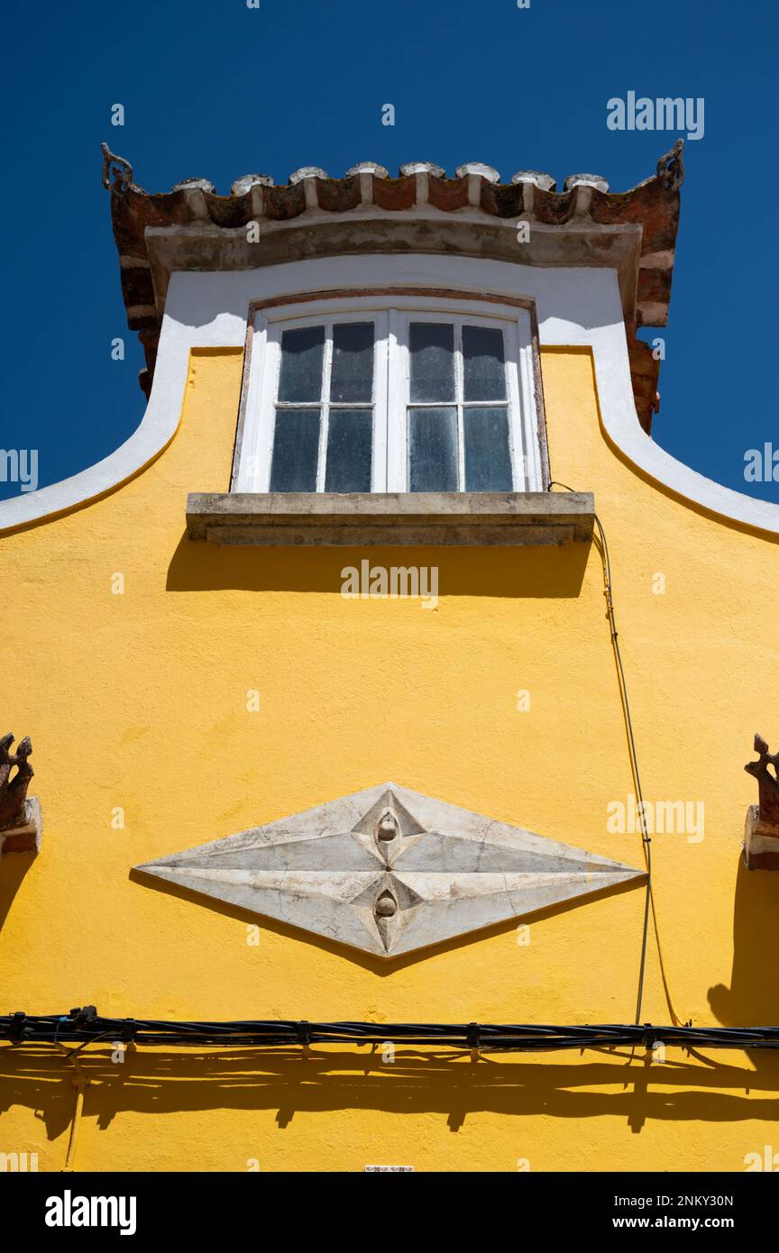 Un edificio dipinto di giallo con una finestra bianca in Lagos Algarve Portogallo che mostra l'architettura tradizionale e lo schema colore Foto Stock