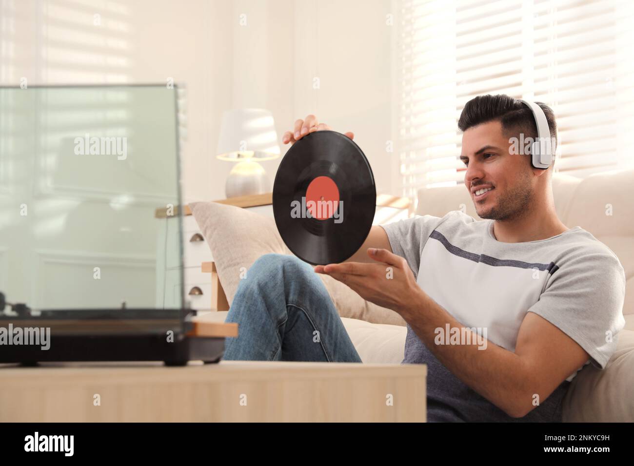 Un uomo felice che ascolta la musica con il giradischi a casa Foto Stock