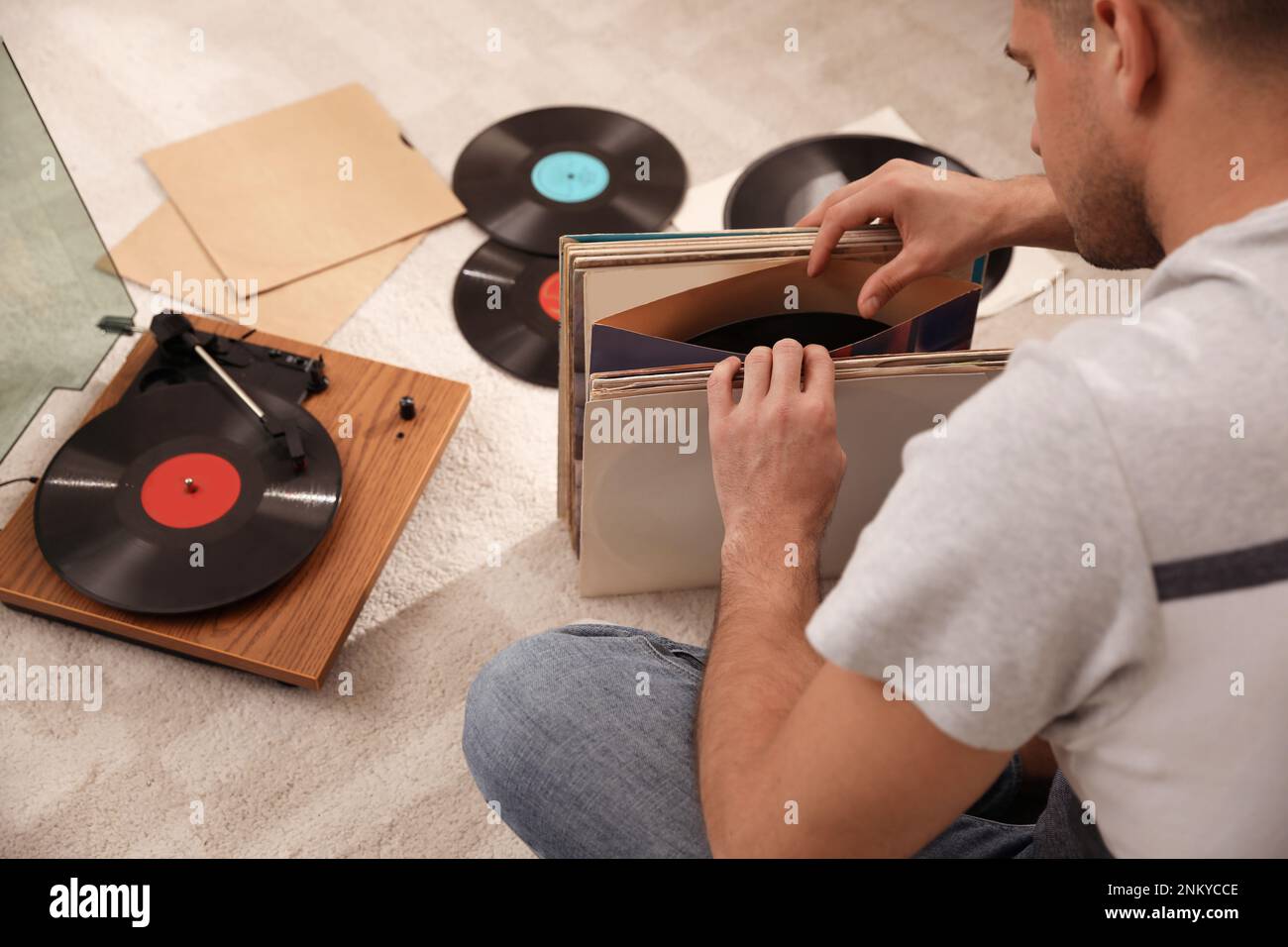 Uomo con collezione di dischi in vinile vicino al giradischi a casa Foto Stock
