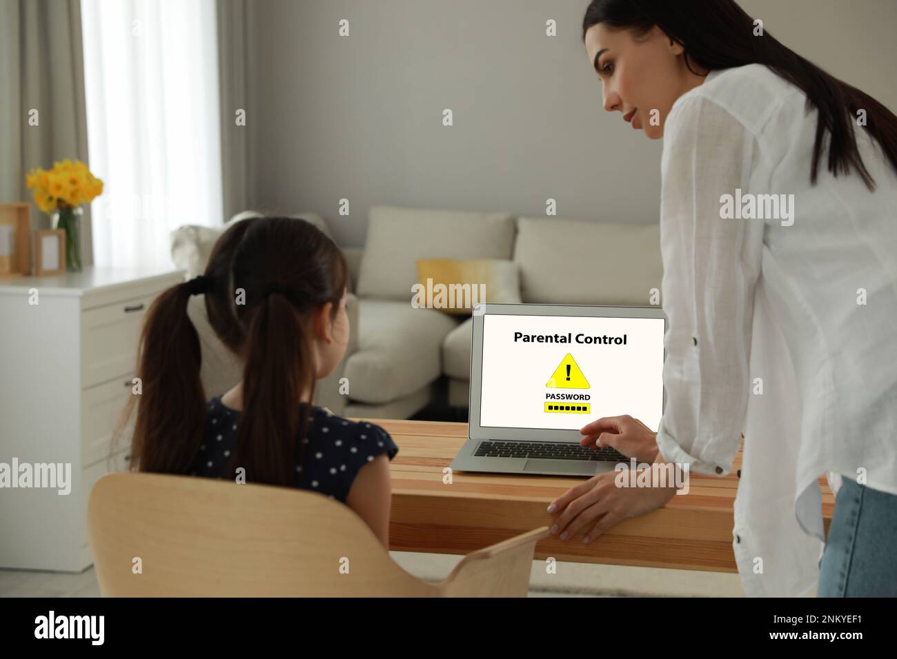 Madre installa l'app di controllo genitori sul computer portatile per garantire la sicurezza del bambino a casa Foto Stock