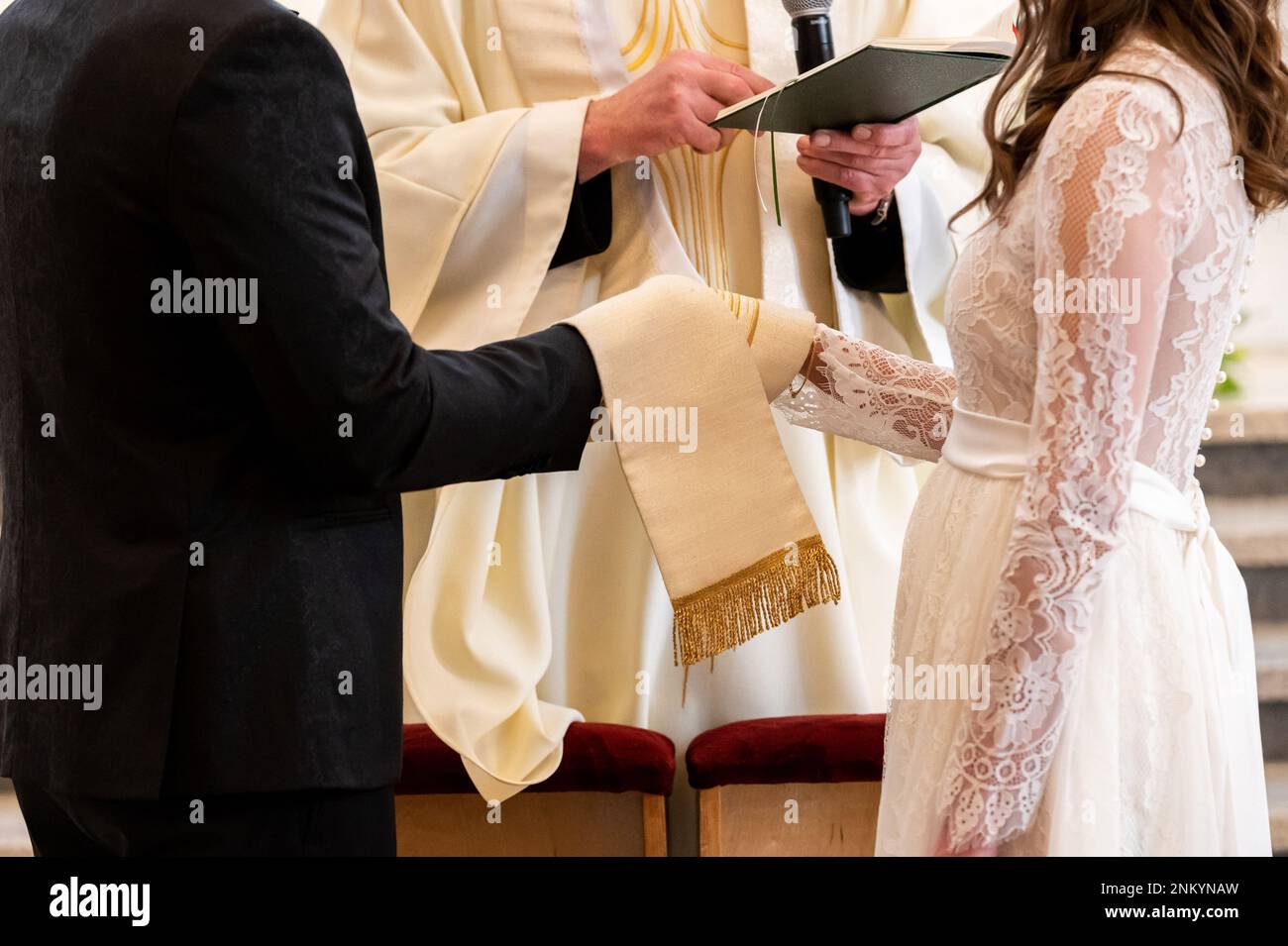 mani, anelli di nozze e voti di matrimonio intrecciate mani della sposa e sposo legato con un nodo di matrimonio Foto Stock