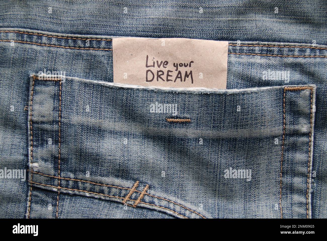 Vivi il tuo concetto di sogno. Virgolette motivazionali iscrizione su un tag in una tasca di jeans blu. Foto Stock
