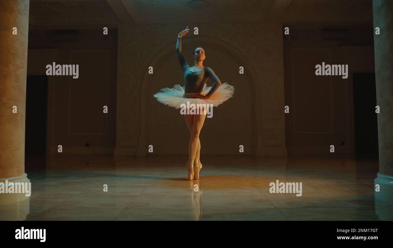 Ripresa cinematografica di una bella ballerina classica femminile in tutu bianco che balla nella lobby del teatro e si prepara ad iniziare lo spettacolo. Coreografia prima dell'inizio dello spettacolo. Balletto classico art. Foto Stock