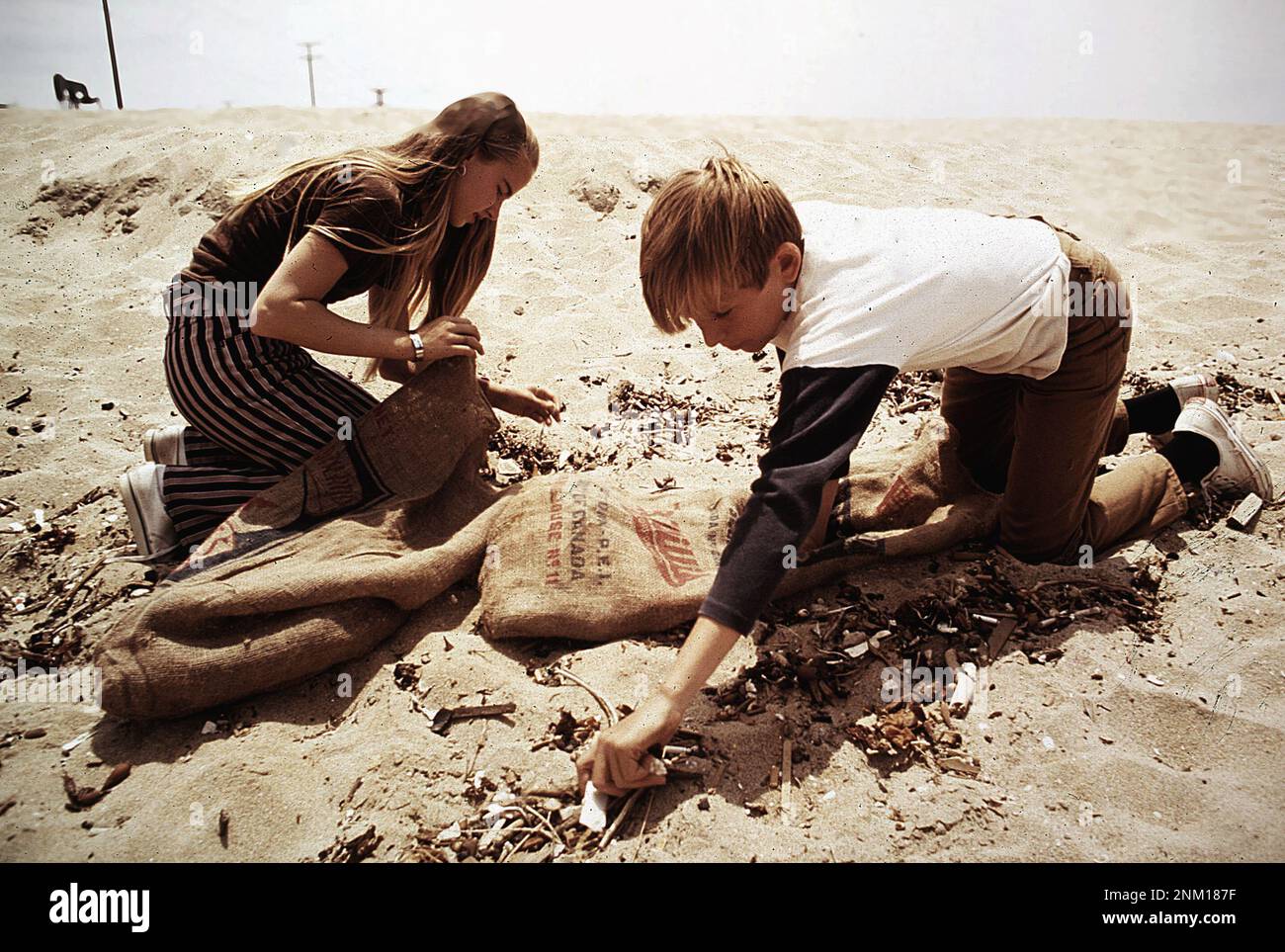 1970s Stati Uniti: Studenti di ottava classe da St. Bonaventure High School trascorrere periodo di recesso raccogliendo cucciolata sulla spiaggia vicino pozzi di petrolio ca. 1972 Foto Stock