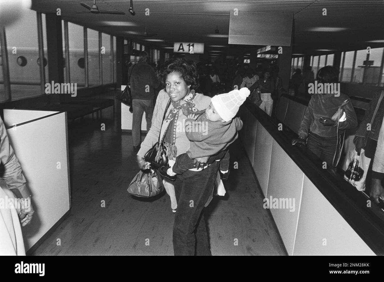 Olanda Storia: Arrivo a Schiphol dell'aereo 1st da Paramaribo dopo un colpo di stato militare, una madre con il bambino tra le braccia ca. Febbraio 29, 1980 Foto Stock