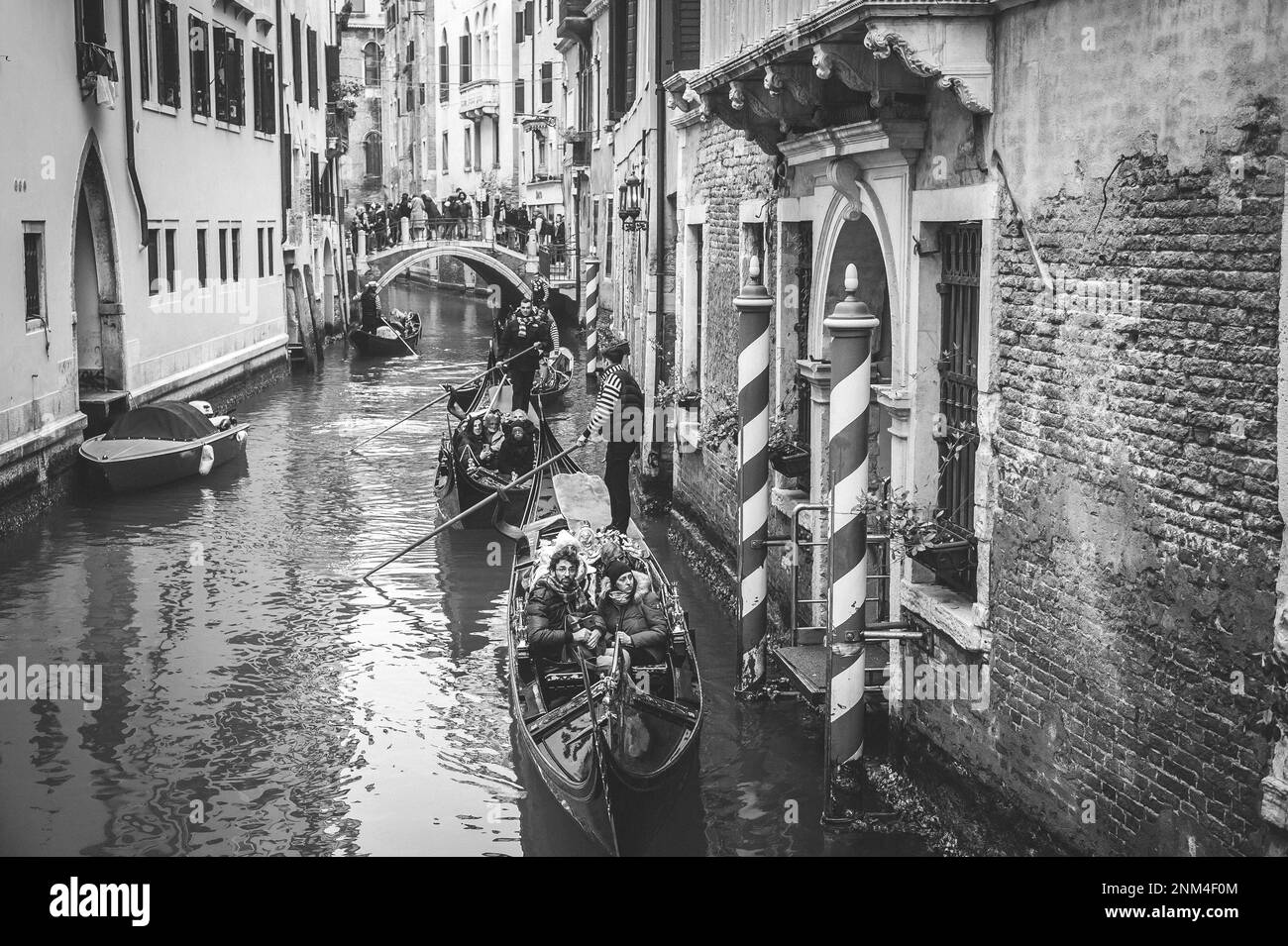 Vista B/N di un canale a Venezia con molti turisti in gondola Foto Stock