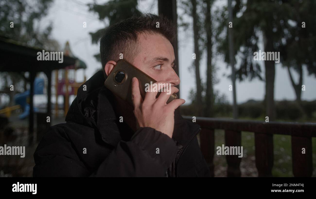 Giovane uomo con i capelli corti che laughing e che parla al telefono nel parco Foto Stock