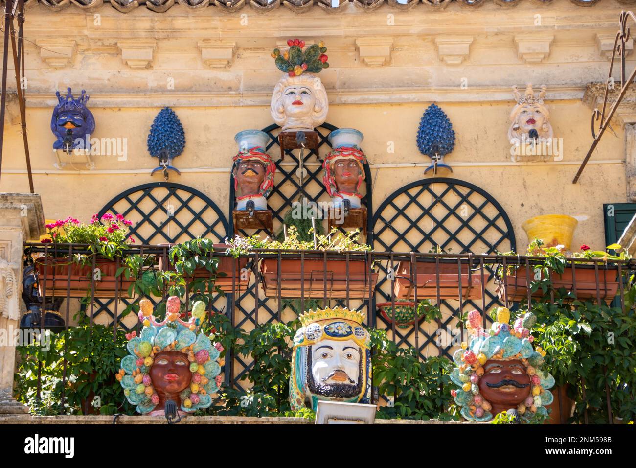 A Palazzolo Acreide , Italia , il 03 - 08 - 2022 - Ceramica tradizionale teste e coni di pino su un balcone barocco, Sicilia, Italia Foto Stock